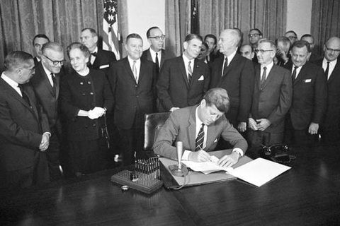 President John F. Kennedy signing the Community Mental Health Centers Act, surrounded by officials