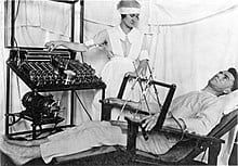 A patient receiving early electroshock treatment in a hospital bed